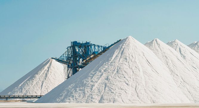 White mountains of salt for the early collection of road salt against a light blue sky